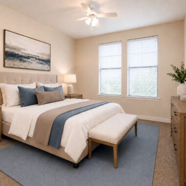 living room with large windows and carpet and bed, nightstands, bench, and dresser with neutral and blue accent decor